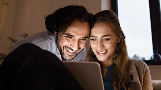 Lykkeligt par kigger på en bærbar computer sammen