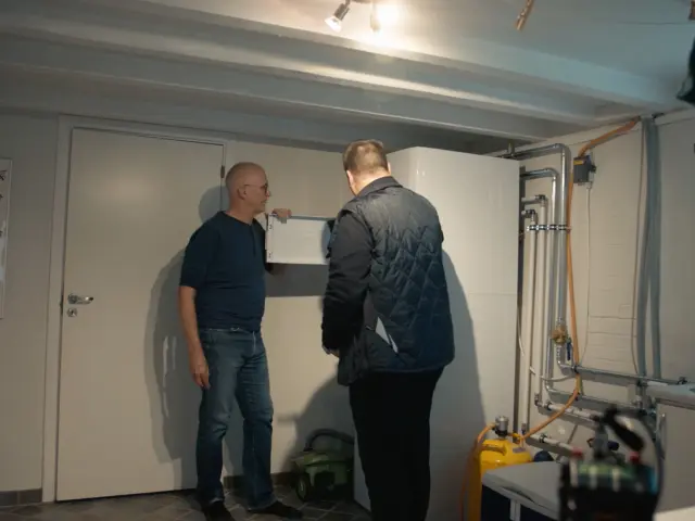 Iversen og en tekniker kigger på en varmepumpe